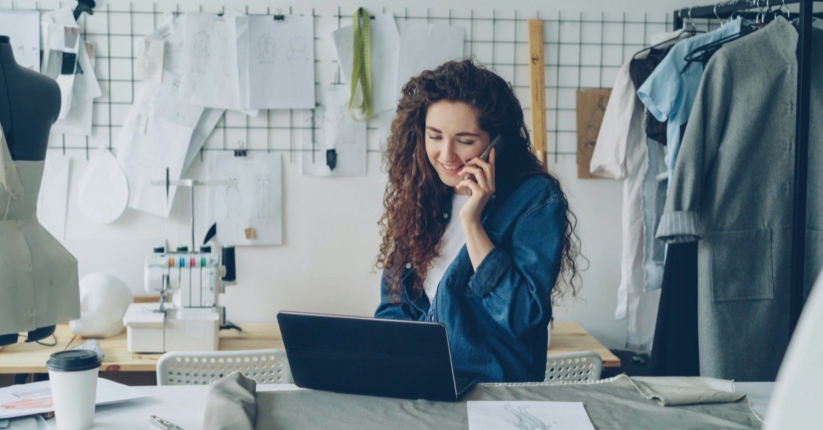 Dirigeante d'une petite entreprise gérant son activité au téléphone tout en travaillant sur son ordinateur portable